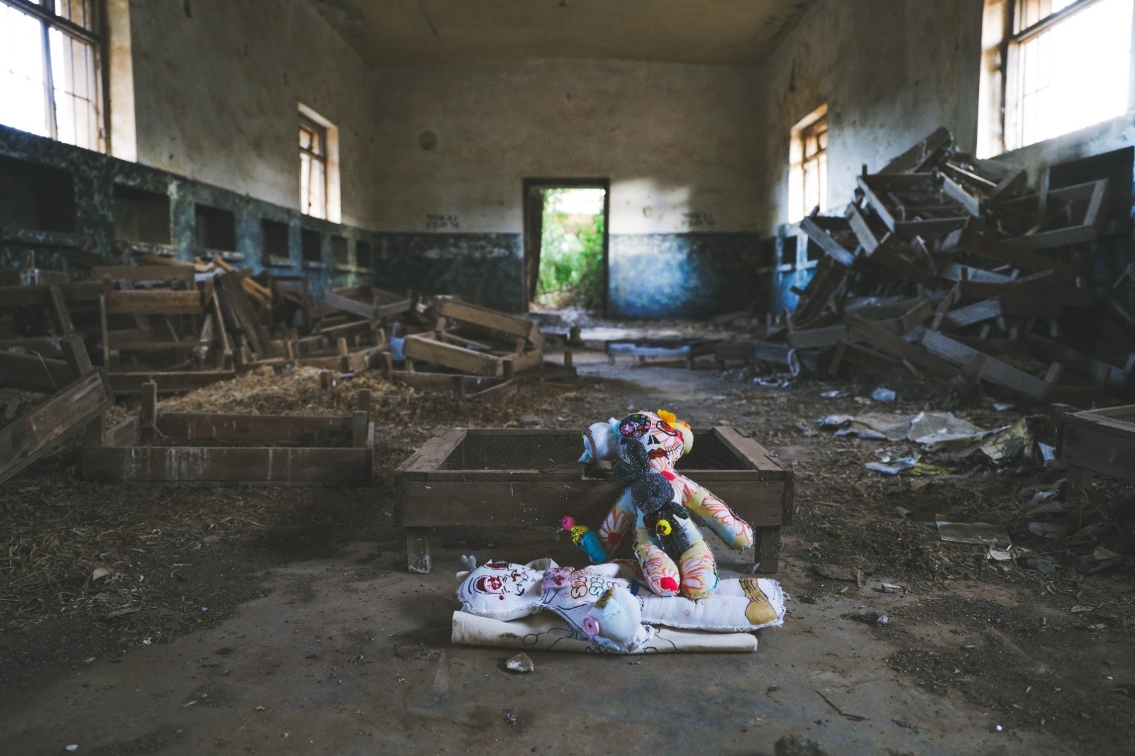 Two hand-sewn dolls with painted faces in an abandoned, ruined hall