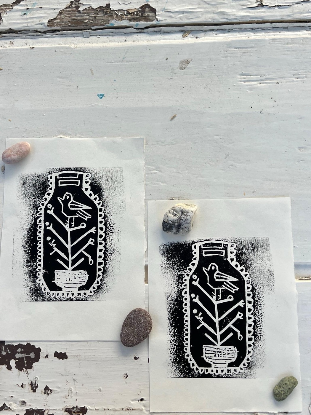 Two black-and-white prints of a bird on a branch inside a jar