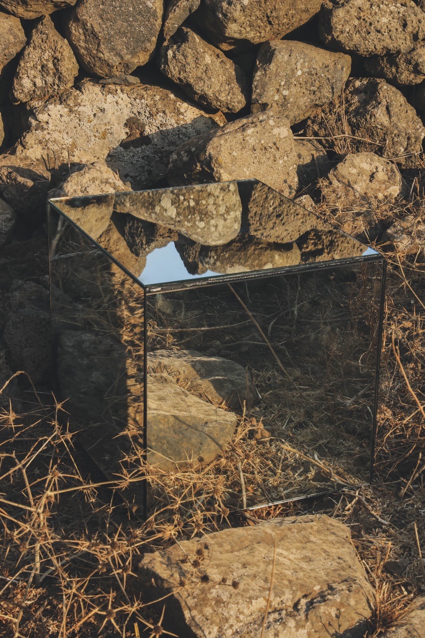 A mirrored cube in golden dry grass