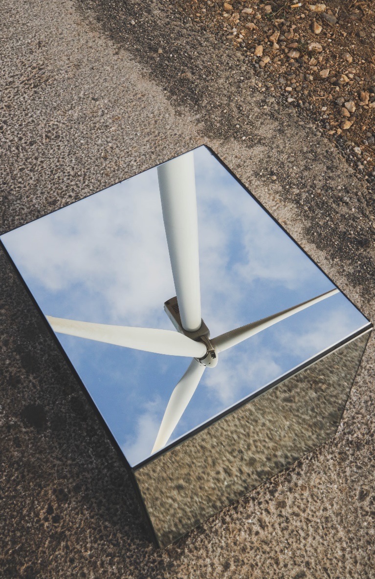 A wind turbine reflected in the top of a mirrored cube